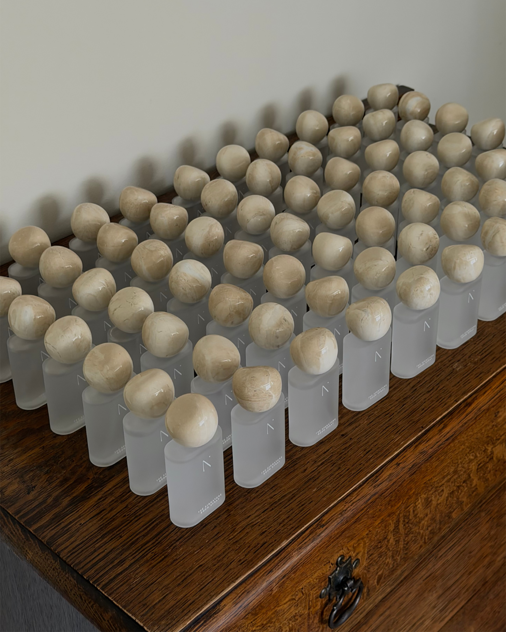 Natural Isle Signature Room Spray, Row of small glass bottles with marble caps on a wooden surface.