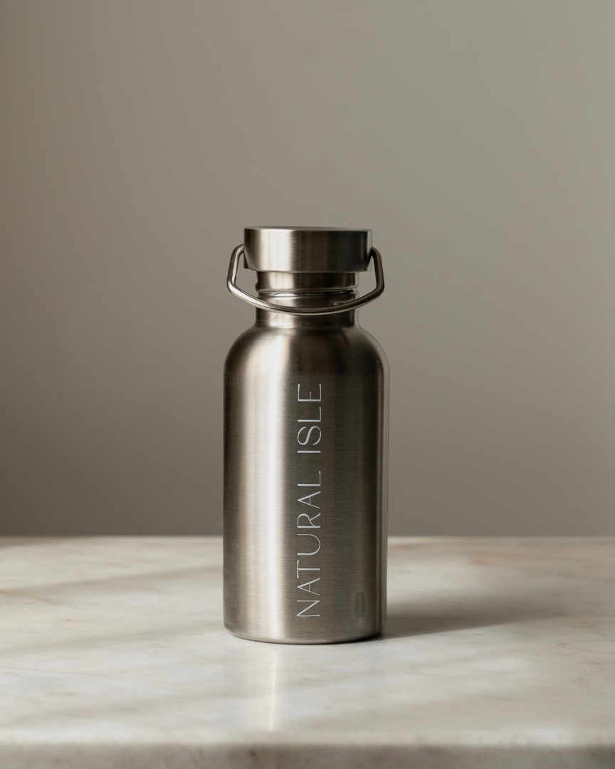 Stainless steel water bottle with 'Natural Isle' branding on a marble surface.