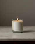Natural Isle Candle in a glass jar with a label on a marble surface and gray background