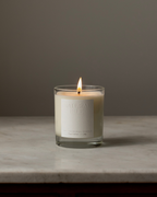 Natural Isle Candle in a glass jar with a label on a marble surface and gray background