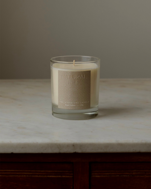 Natural Isle Signature Candle, Candle in a glass jar with a label on a marble surface
