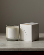 Natural Isle  Candle and its packaging on a marble surface with a neutral background