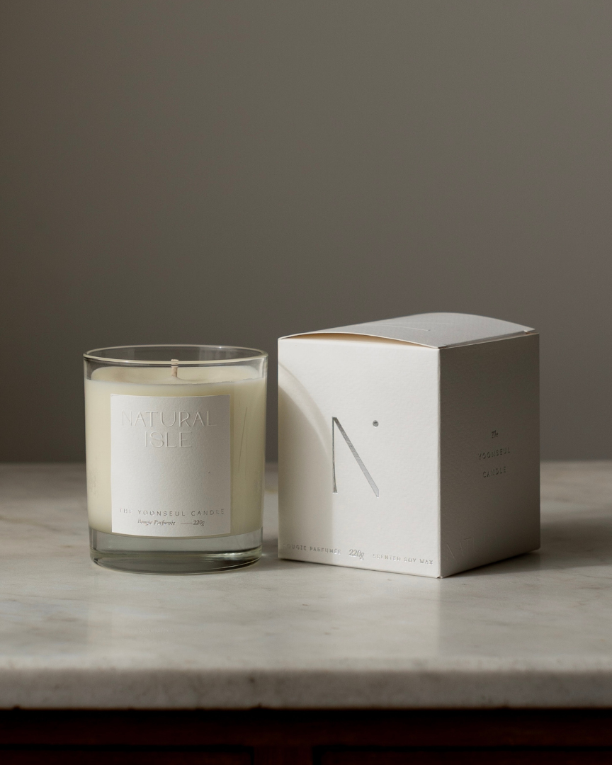 Natural Isle  Candle and its packaging on a marble surface with a neutral background
