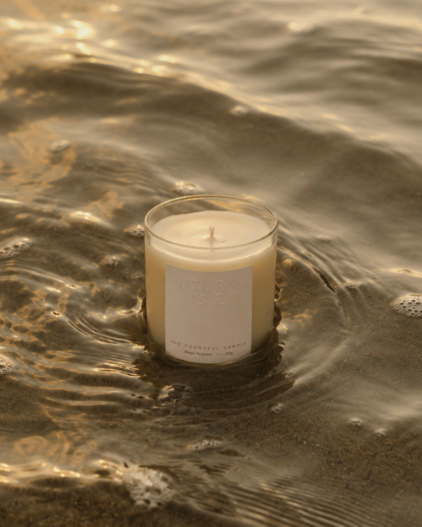 Natural Isle  Candle floating in water with a label on a beach