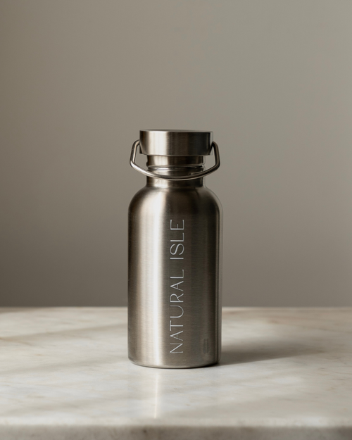 Stainless steel water bottle with 'Natural Isle' branding on a marble surface.